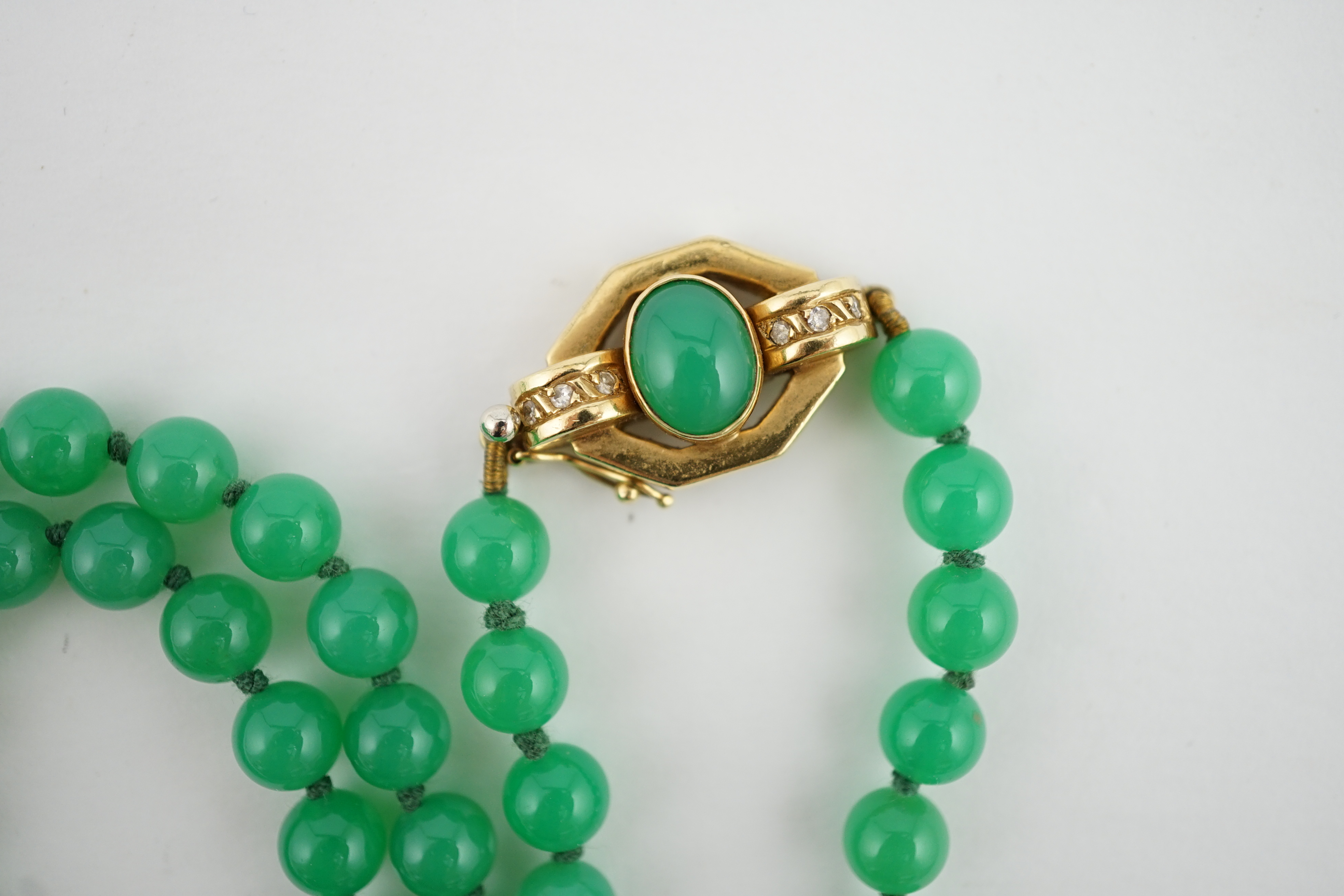 A modern long single strand jadeite bead necklace, with a cabochon jade and diamond chip cluster set 18k clasp